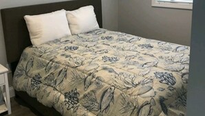 Un dormitorio con cama, mesita de noche y ventana con persianas.