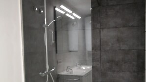 Ein modernes Badezimmer mit einer Dusche in Glaswand, Toilette und Waschbecken.