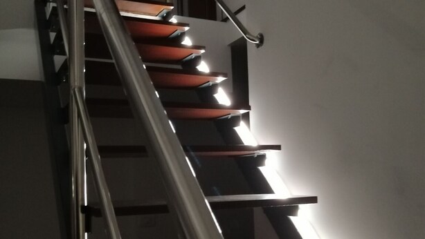 Eine Treppe mit Metallgeländer und Holzstufen.