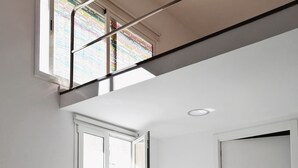 Una sala de estar moderna con un sofá blanco, una mesita y vistas a un ventanal con vidrieras de colores.