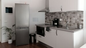 Una cocina moderna con armarios blancos, un refrigerador de acero inoxidable, una cafetera y un salpicadero de azulejos.