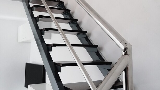 Una escalera moderna con barandillas de vidrio y soportes metálicos.