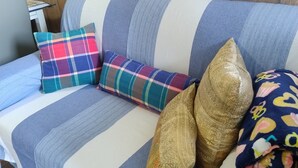 A striped sofa with multiple pillows, a wooden headboard, and a tiled floor.