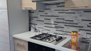 A modern kitchen with a gas stove, oven, and stainless steel range hood.