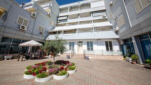 A multi-story building with a central courtyard featuring flower beds and outdoor seating. - Hotel Kojku (Durrës)