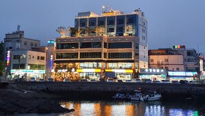 A multi-story hotel with a modern design, featuring large windows and a rooftop garden. - Owl Hotel (Sacheon)