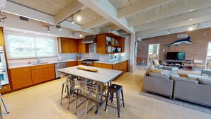 Une cuisine moderne avec des meubles en bois, un plan de travail en marbre et un îlot central doté de tabourets.
