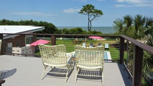 Une terrasse dotée de deux fauteuils en osier blanc, d’une petite table et offrant une vue sur l’océan.