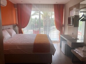 A hotel room with a bed, a desk, a mirror, and a TV. - Akcay Mas Palmiye Otel (Edremit)