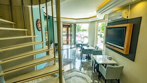 Un moderno vestíbulo de hotel con una escalera, zona de estar y un televisor montado en la pared.