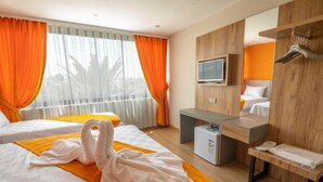 Habitación de hotel con dos camas, un minibar, un televisor y un armario de madera con espejo.
