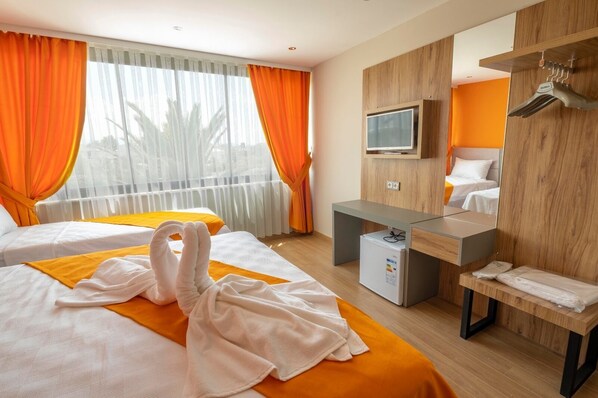 Habitación de hotel con dos camas, un minibar, un televisor y un armario de madera con espejo.