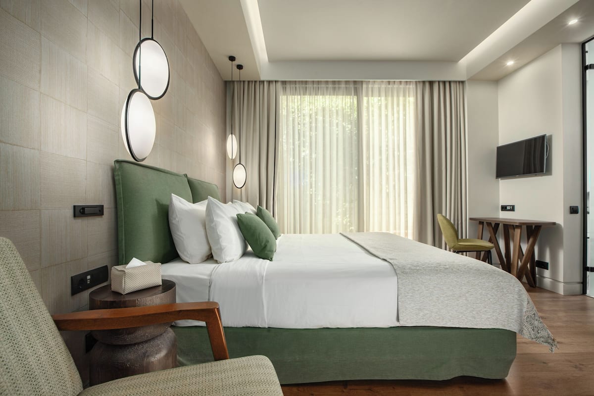 A modern hotel room with a large bed, a desk, and a television.