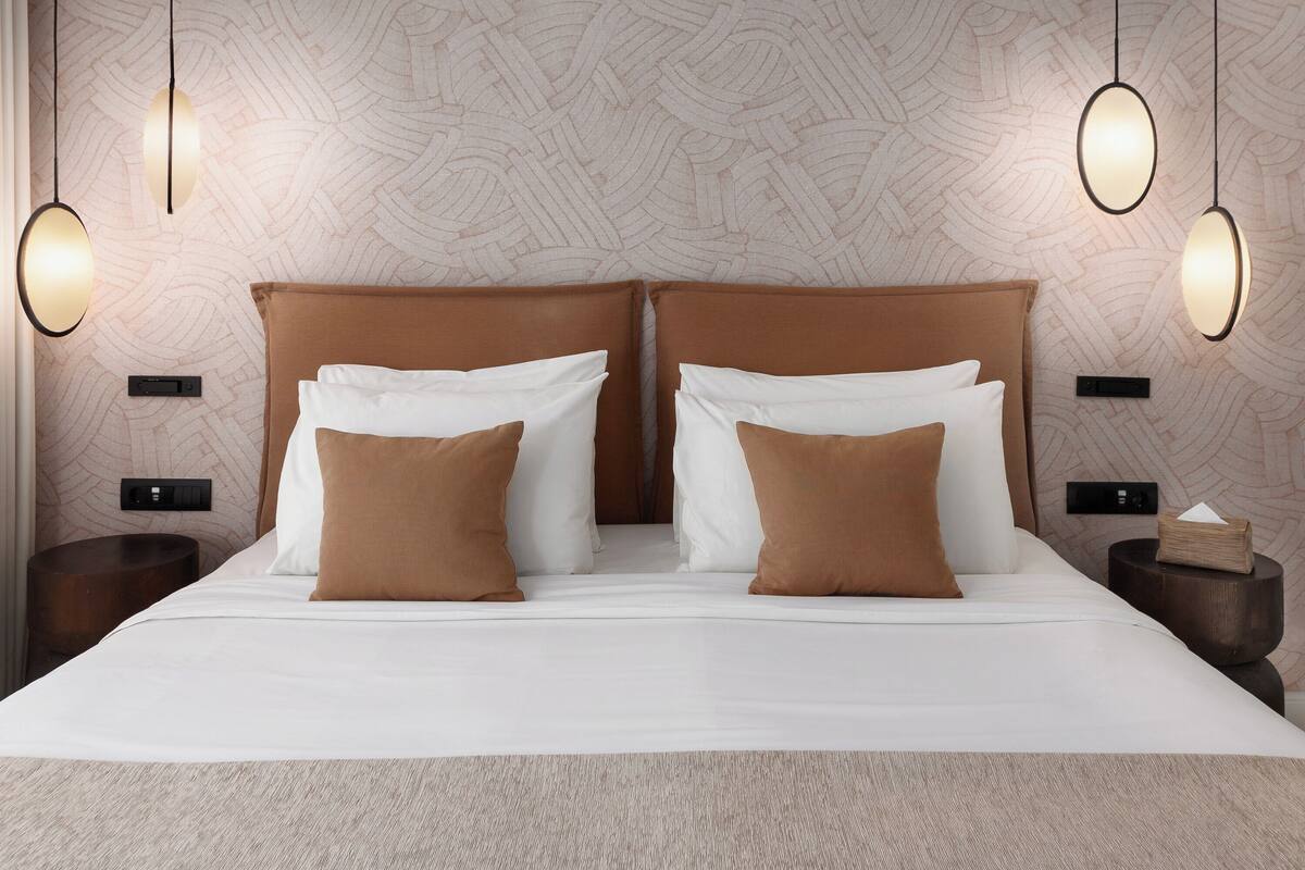 A double bed with a headboard, two bedside tables, and two wall-mounted lamps.