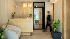 A modern reception area with a sofa, potted plants, and a glass door leading to a hallway. - The Residence - Christokopidou Hotel & SPA (Athens)