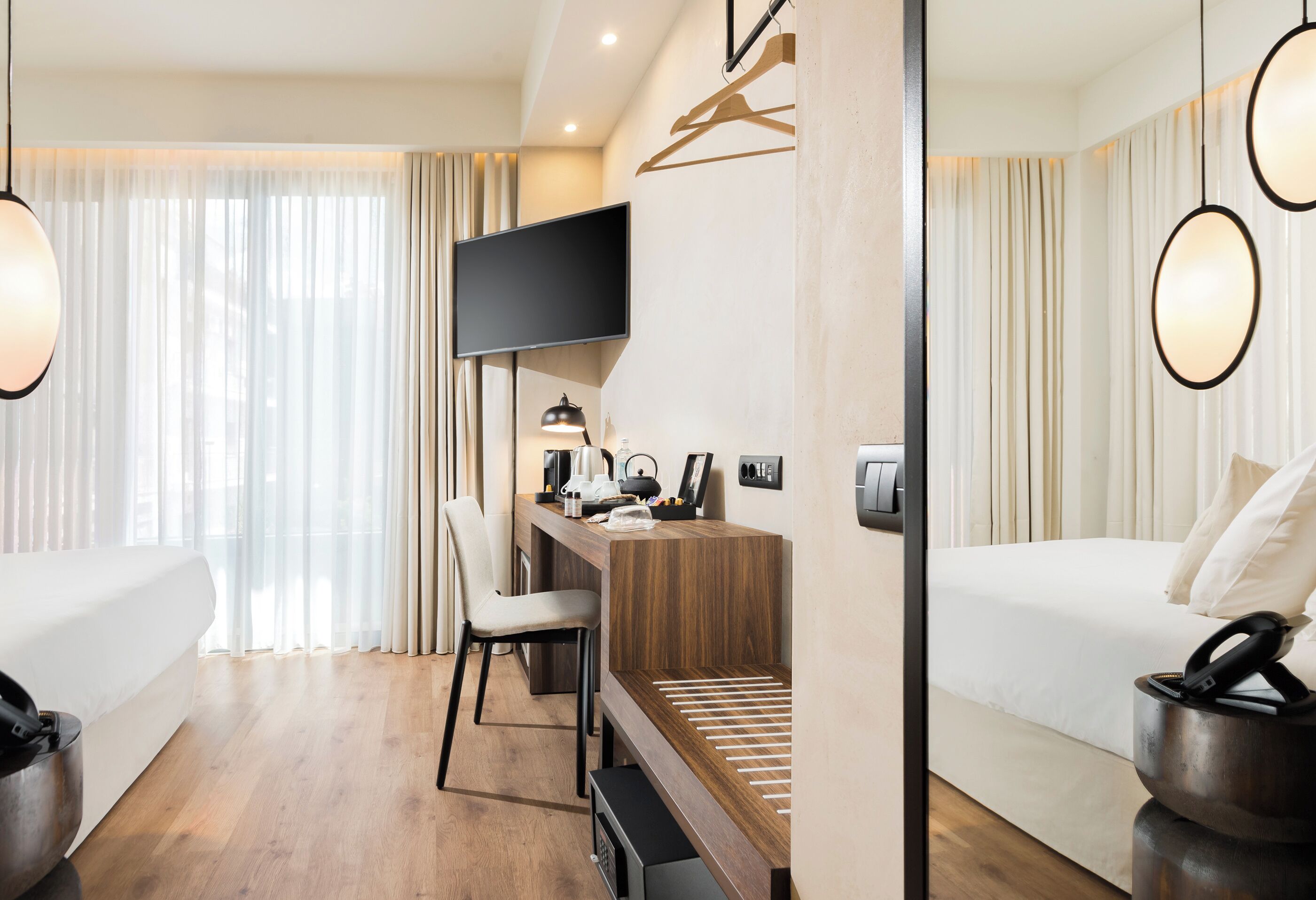 A modern hotel room with a bed, desk, chair, and a television.