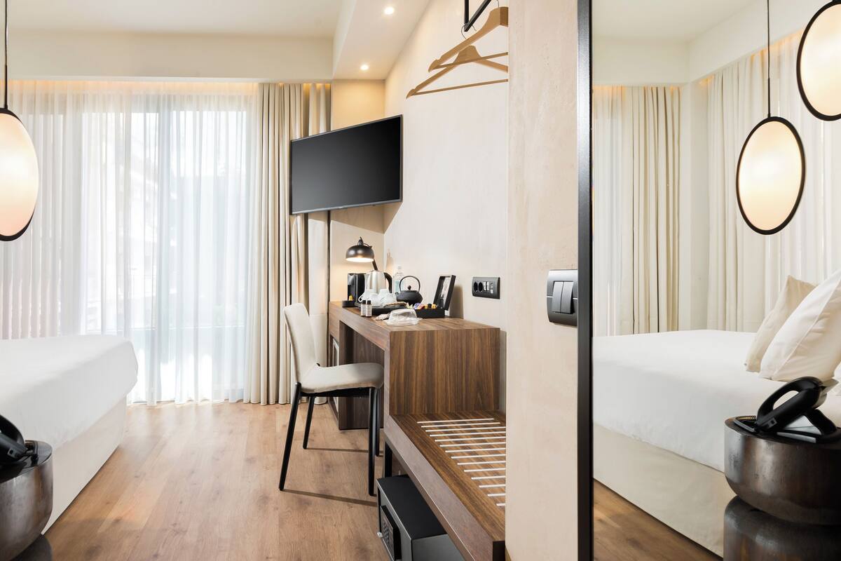 A modern hotel room with a bed, desk, chair, and a television.