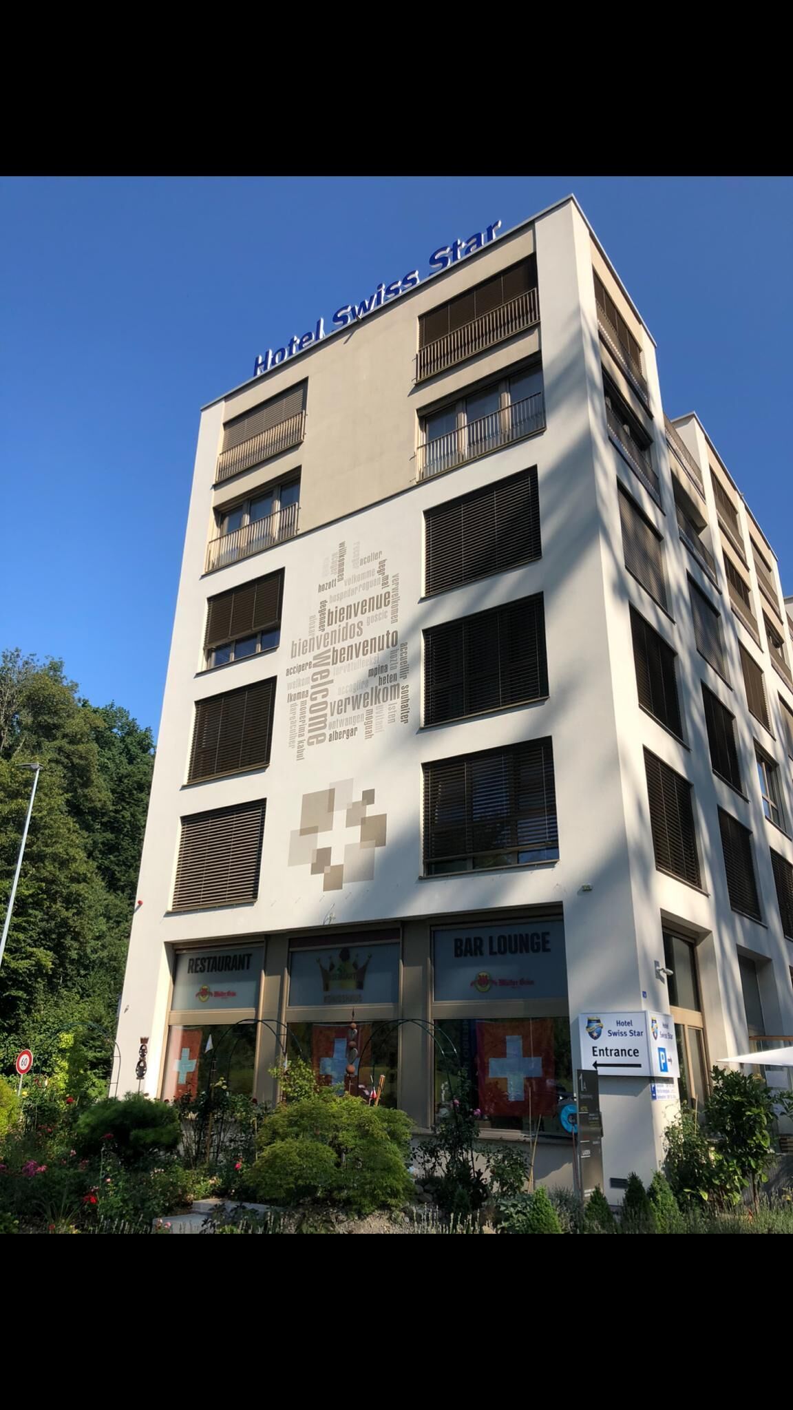 Et hotel i flere etager med et skilt der siger "Hotel Swiss Star" og en ordsky på facaden.