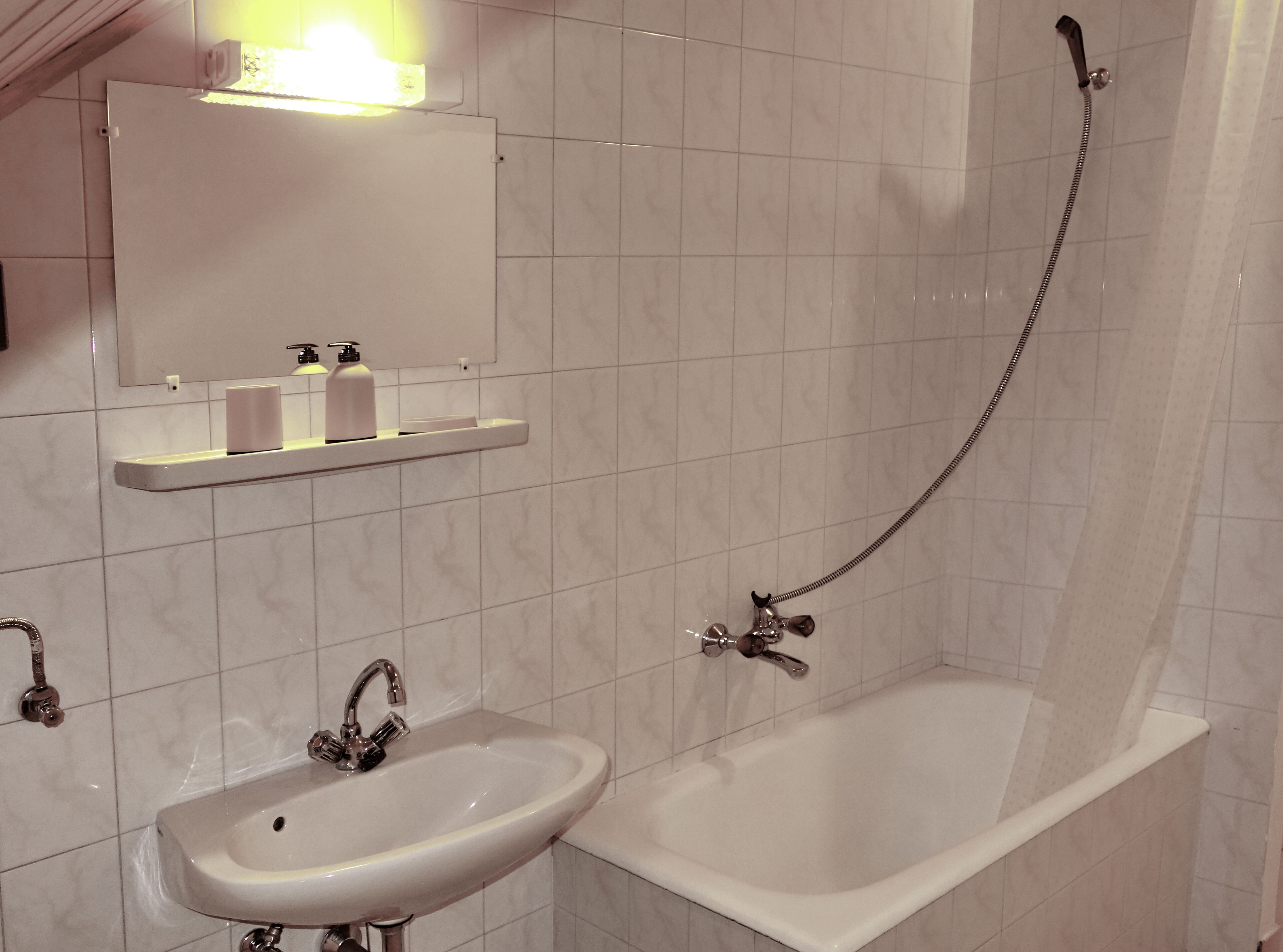 A bathroom with a sink, mirror, and shower.