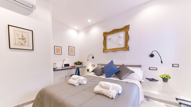 Ein modernes Hotelzimmer mit einem großen Bett, einem Nachttisch, einem Schreibtisch und einem Badezimmerbereich.