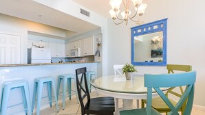 Una cucina moderna con mobili bianchi, un tavolo da pranzo in vetro e sedie blu.