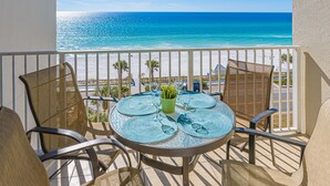 Un balcone con tavolo, sedie e vista sull'oceano.