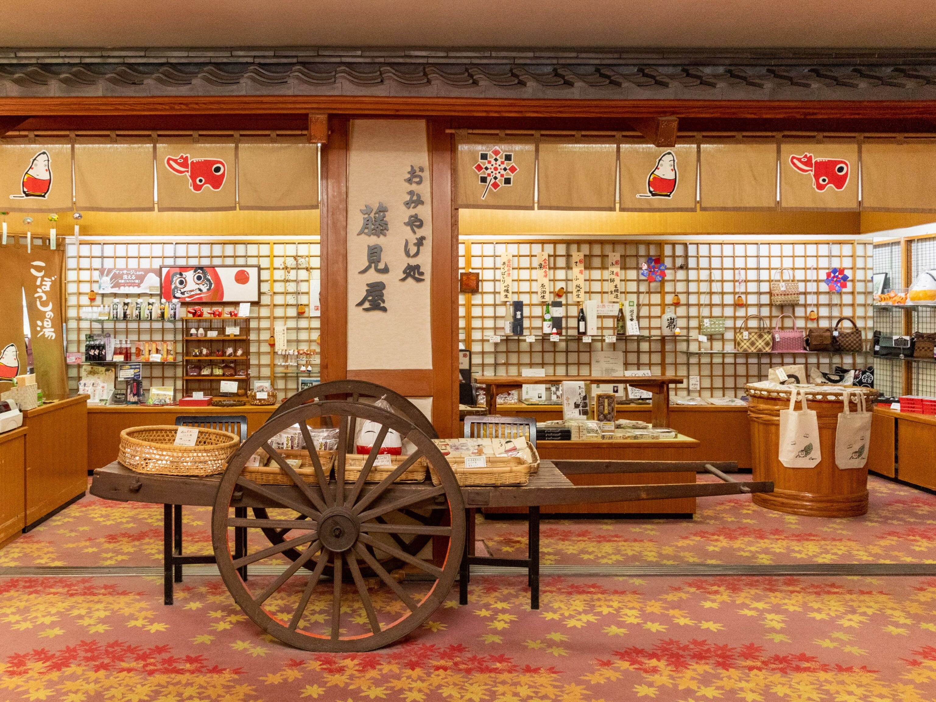 A traditional Japanese store with wooden interiors, a central display table, and a decorative wooden cart.