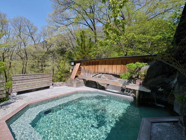 A clear pool surrounded by wooden structures and natural scenery.