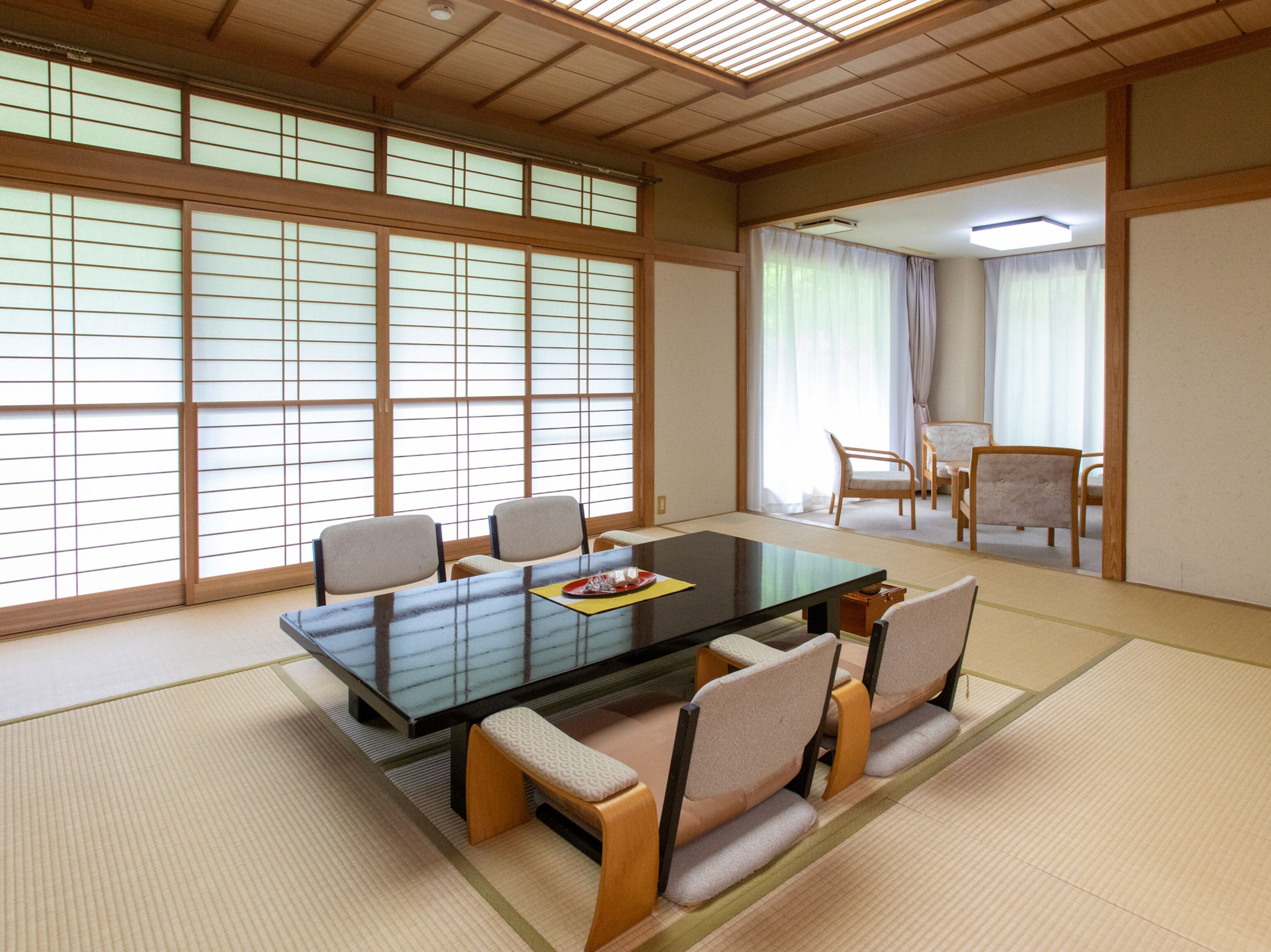 A traditional Japanese room with tatami flooring, a low table, and chairs.