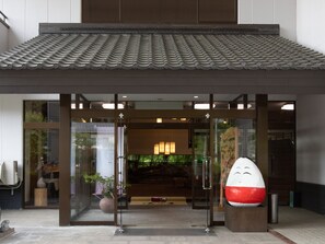 A traditional Japanese building with a tiled roof, large glass doors, and a modern interior visible through the entrance.