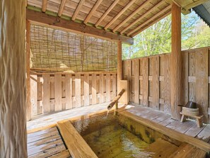 A wooden hot tub area with a bamboo screen, wooden deck, and a wooden bench.