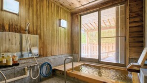 Una cabaña de madera con jacuzzi, zona de ducha y un amplio ventanal.