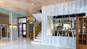 A spacious lobby with a wooden staircase, a reception desk, and a large window with a view of the interior. - Pey Resort (Sort)