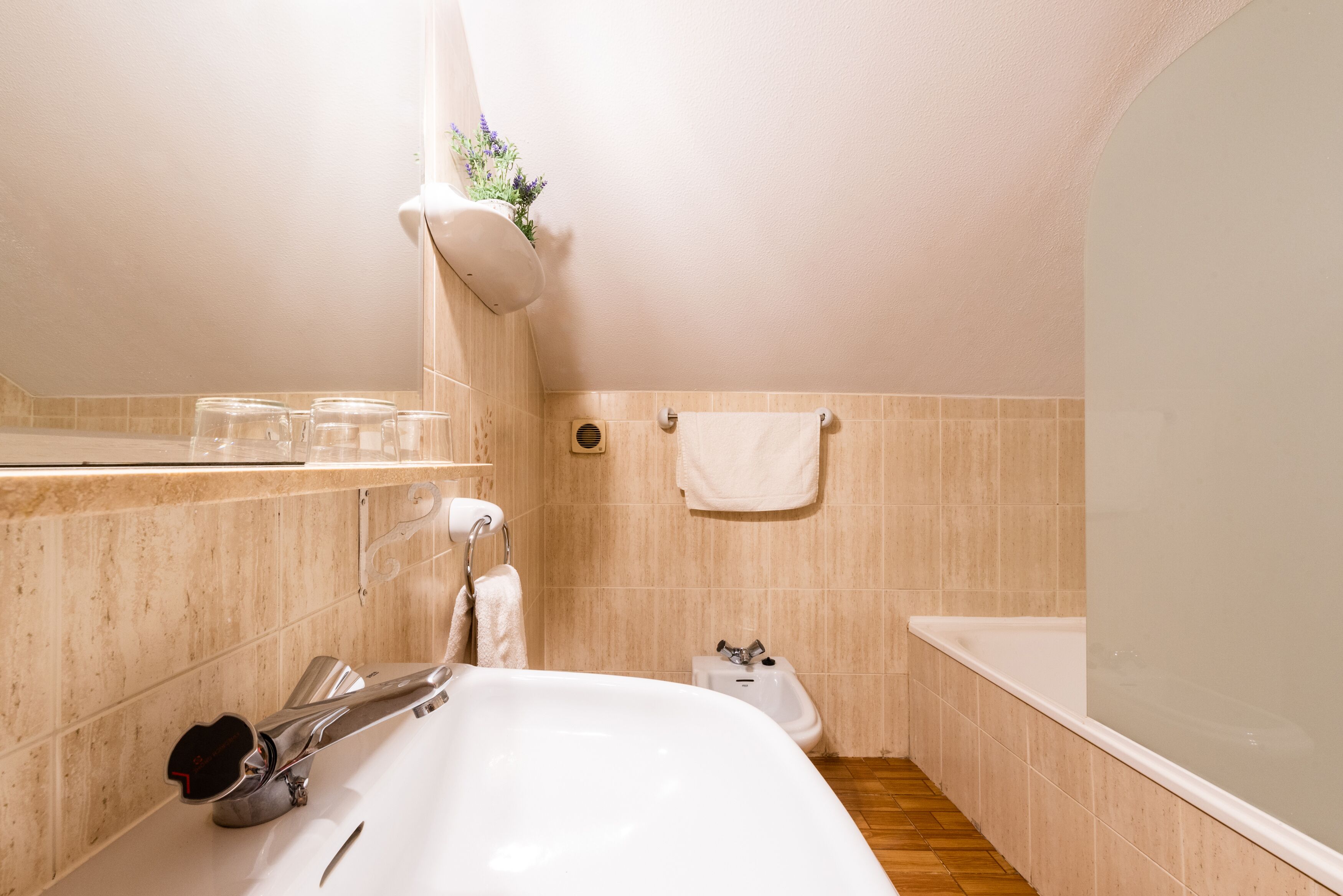 A bathroom with a white sink, a bidet, a towel rack, and a shower area.