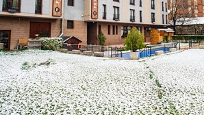 A multi-story hotel with a prominent 'PEY RESORT' sign, a covered outdoor seating area, and a snow-covered courtyard. - Pey Resort (Sort)