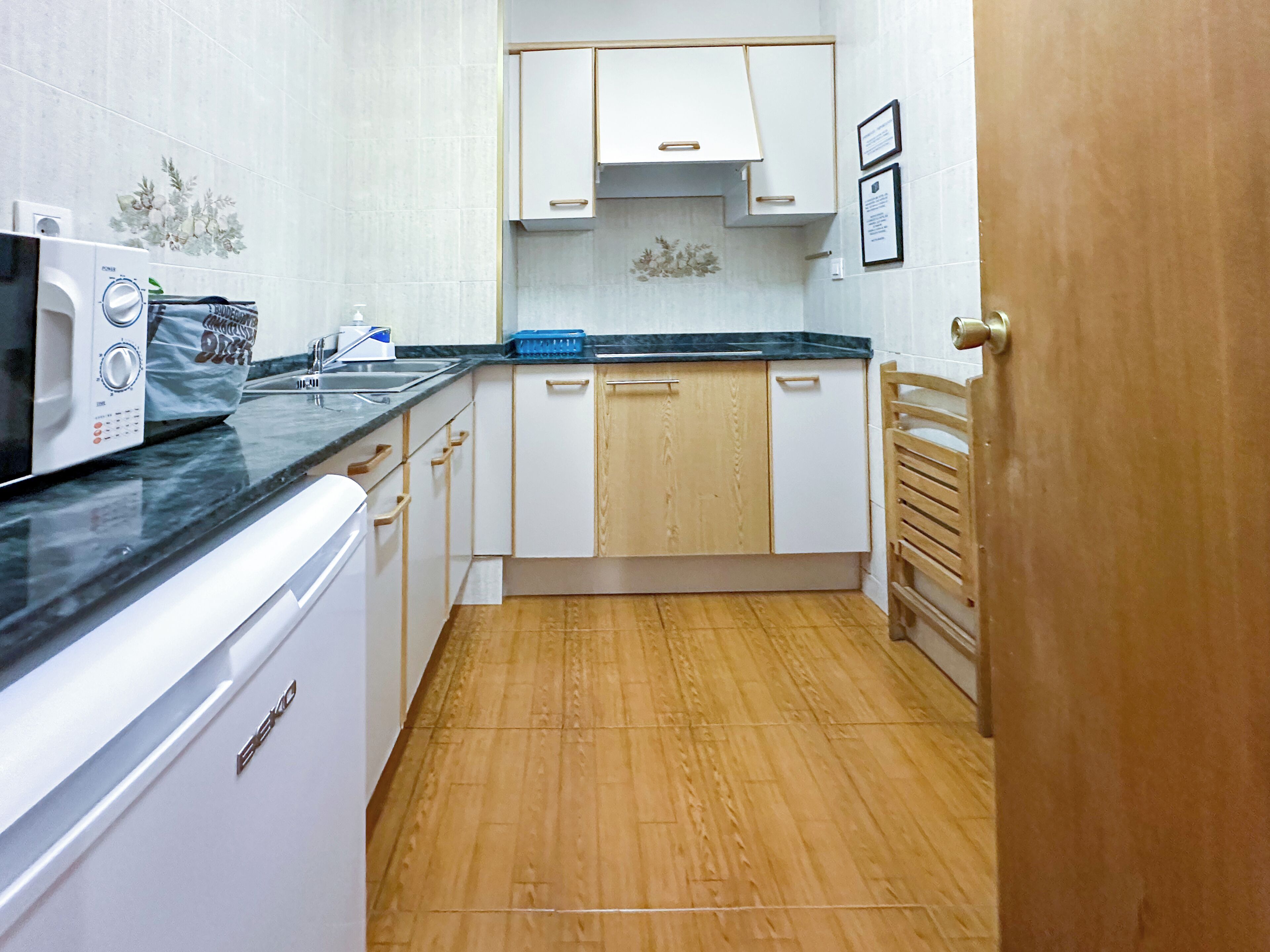 A compact kitchen with white cabinets, a microwave, and a dishwasher.