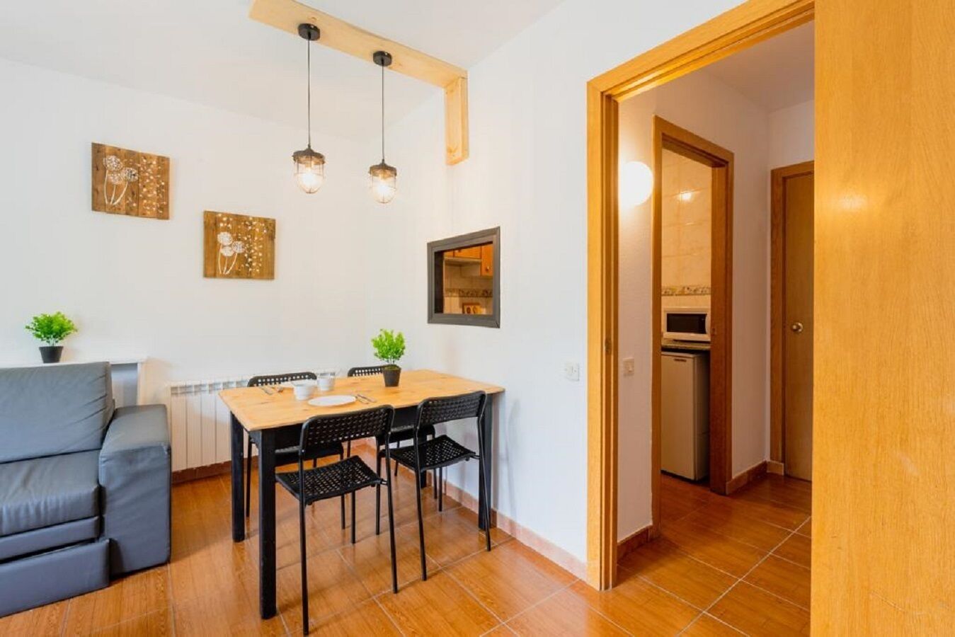 Un espacio habitable compacto con comedor, un sofá gris y una kitchenette.