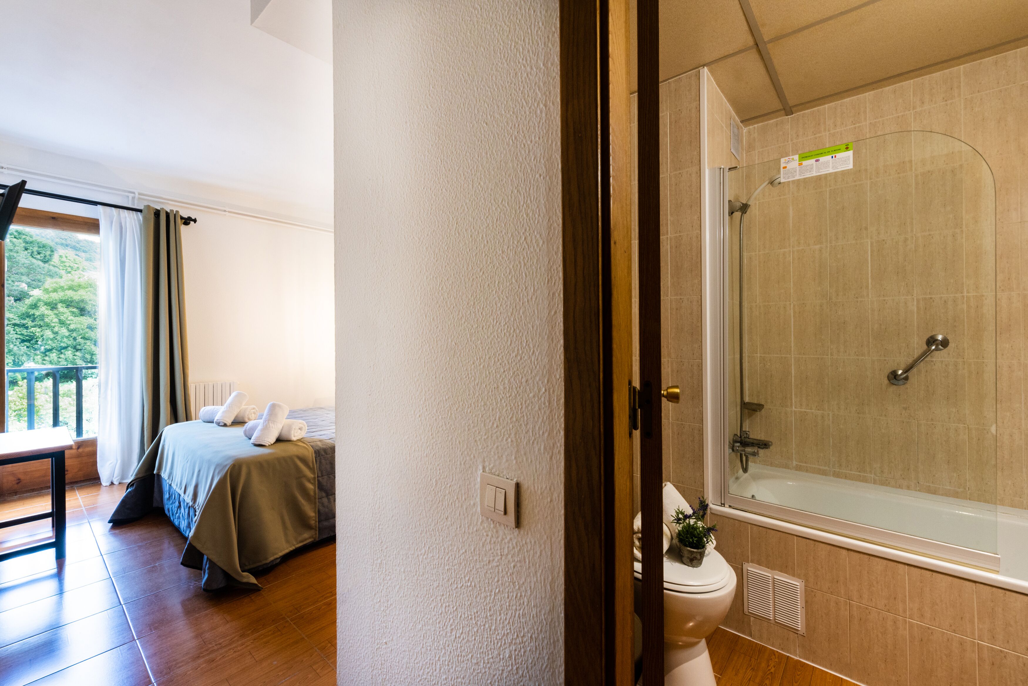Quarto com cama, janela com cortinas e varanda.