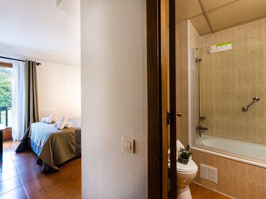 Quarto com cama, janela com cortinas e varanda.