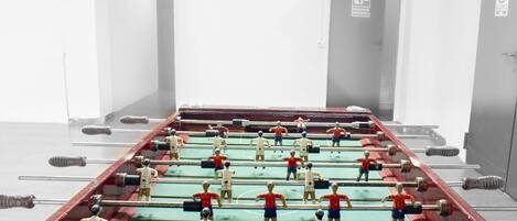 A foosball table in a room with white walls and doors.