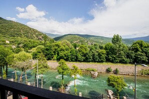 A river with a bridge, surrounded by lush greenery and hills. - Pey Resort (Sort)