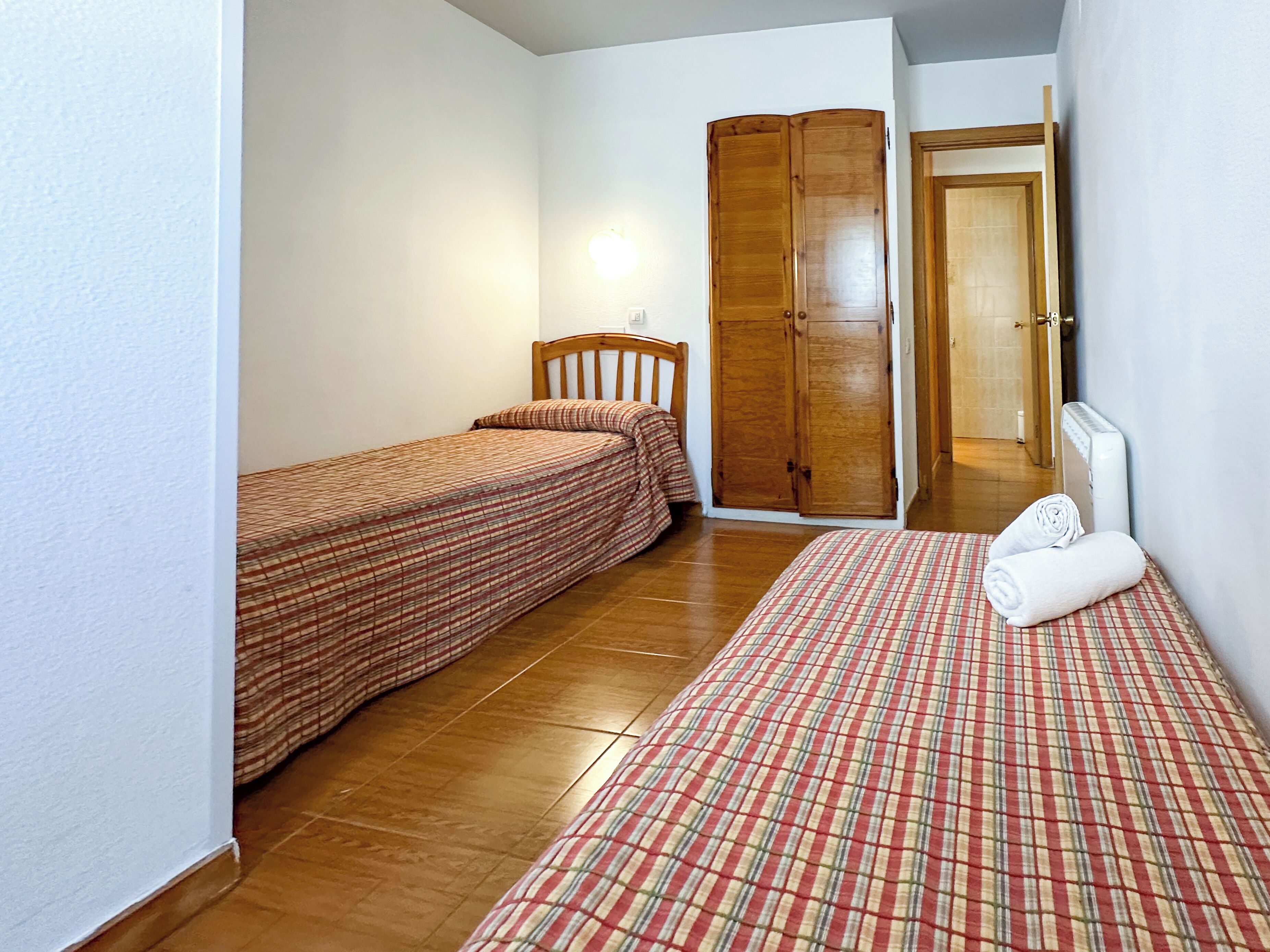 A bedroom with two beds, a wardrobe, and a bathroom visible through an open door.