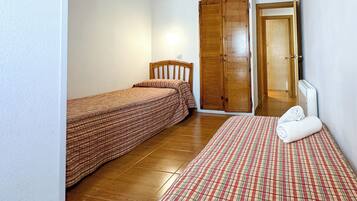 Une chambre avec deux lits, une armoire et une salle de bain visible à travers une porte ouverte.