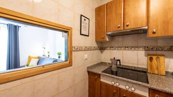 A compact kitchen with wooden cabinets, a built-in stove, and a window with curtains.