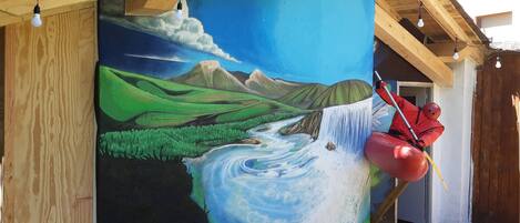 Un mural que muestra un río y montañas en la pared exterior de un edificio.