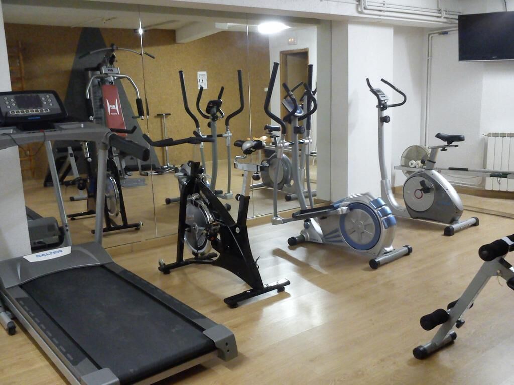 A gym with various exercise equipment including treadmills, stationary bikes, and elliptical machines.