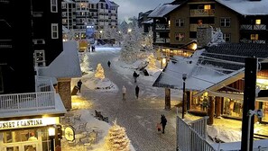 Lumipeitteinen katu, jossa on rakennuksia, näkyvissä oleva ravintola nimeltä ’Sunset Cantina’ ja joulukuusi.