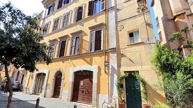 A multi-story building with a yellow facade, arched doorways, and a bicycle parked outside.