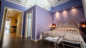 A bedroom with a bed, a chair, and a nightstand. There is a door leading to another room.