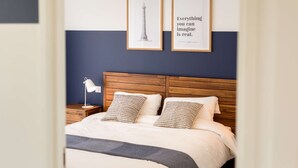 A neatly made bed with a wooden headboard, two framed pictures on the wall, and a bedside lamp. - Port Ste-Marine: L'Escale - Balconies & Small view (Combrit)
